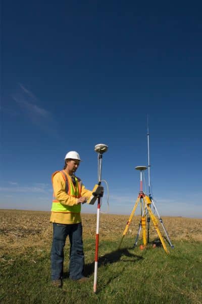 Land surveyor using GPS equipment to mark accurate property boundaries before fence installation