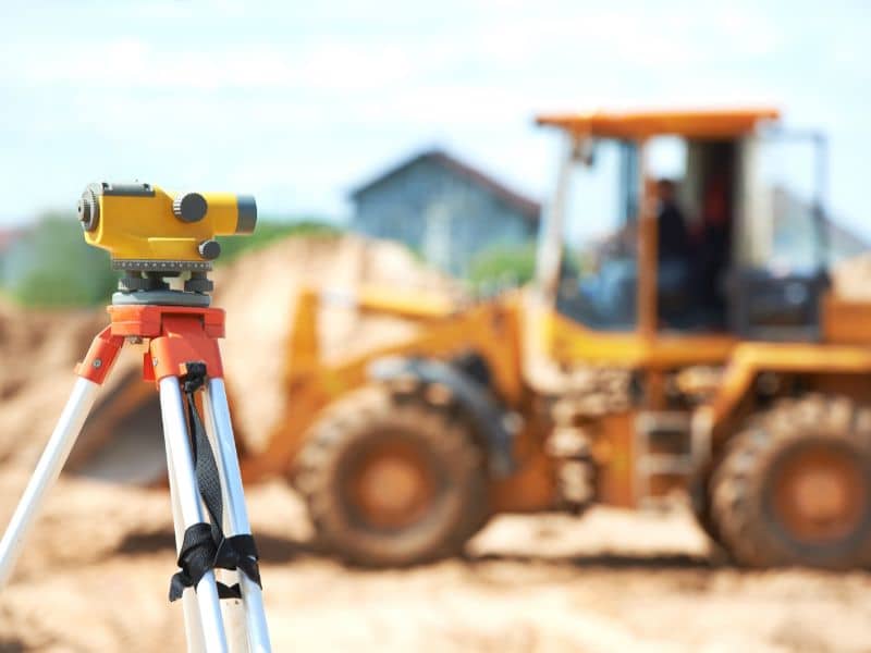 Land surveyor equipment with tripod and construction site showing surveying work in Dothan Alabama